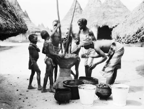 Women and boys extracing palm oil using mortar and pestle