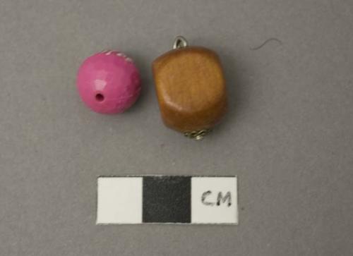 2 Beads; one circular, dyed pink; 1 wood, rectangular, with metal fastening