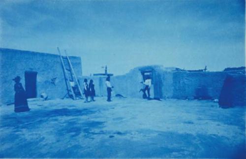 5 Pueblo men and women standing in courtyard