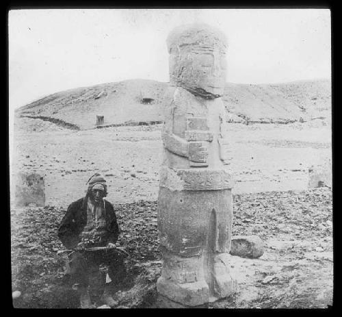 Man sitting by large carved stone figure