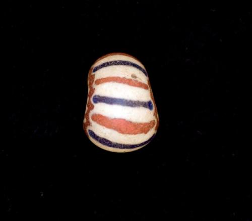 Glass, red bead fragment with white and blue streaks