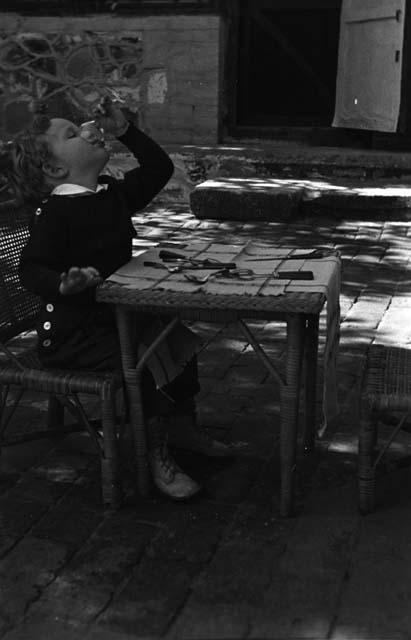 Nebe Johnson drinking at small table in temple courtyard