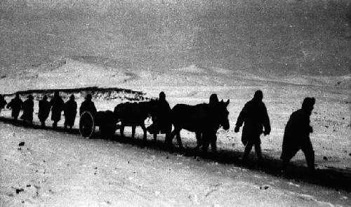 Line of soldiers with horses and carts walking through snow