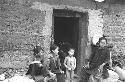 Woman and three children around doorway of mud brick building