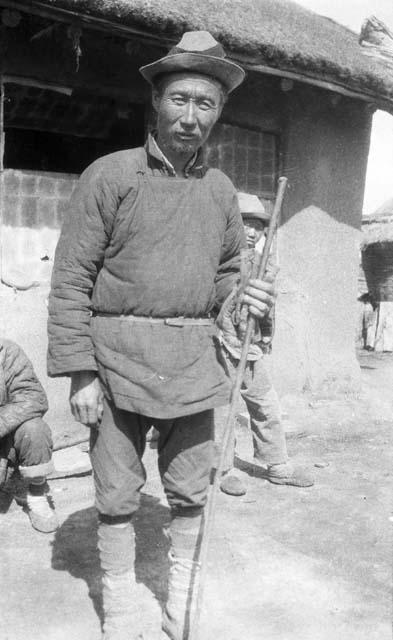 Portrait of an older fish skin man standing holding a staff