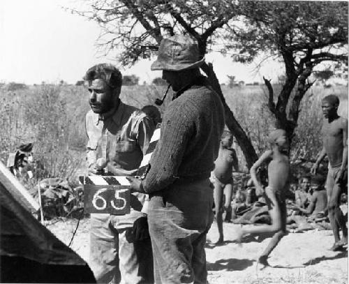 Daniel Blitz and Casper Kruger demonstrating how to put numbers on a camera roll, with a group people sitting and standing in the background