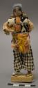 Doll, man with seed pod vessel and back bundle, affixed to stand