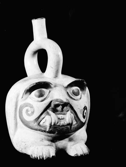 White stirrup vessel, human head with fangs in relief