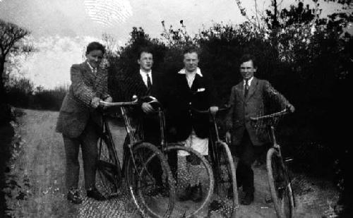 Four young Western men standing beside bicycles