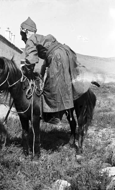 Old lama mounting a horse