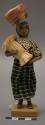 Doll, woman with basket on head and plant fiber bundle, affixed to stand