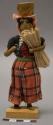 Doll, woman with covered box on head, affixed to stand