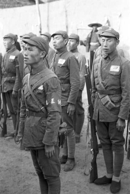 Two rows of soldiers with one soldier standing up front