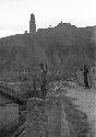 Soldier standing guard along top of and worker standing next to stone wall