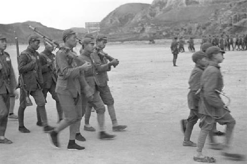 Group of soldiers marching, cliff visible in distance