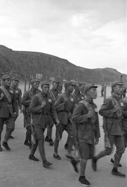 Group of soldiers marching, cliff visible in distance