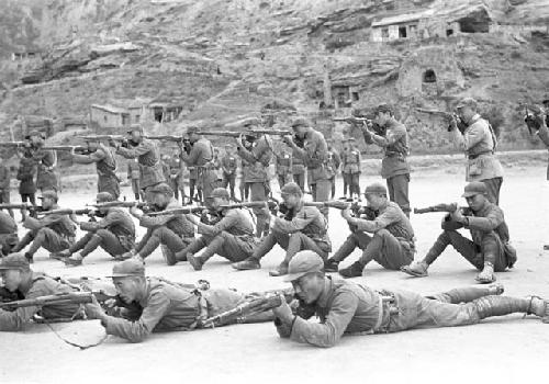 Three rows of soldiers in different stances during military drill