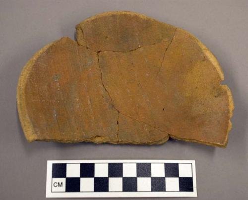 Fragments of base of orange pottery jar used as plate