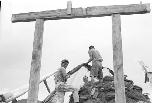 Three men hauling nets in front of wooden altar