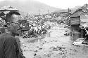 Man with glasses standing in front of a slum