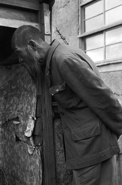 Man looking into room as he waits outside