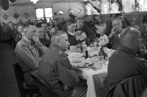 Soldiers sitting at table looking ahead listening