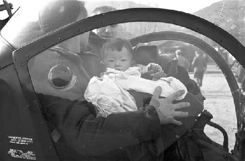 Soldier holding baby in helicopter