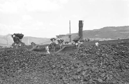 Workers hauling rocks off boat