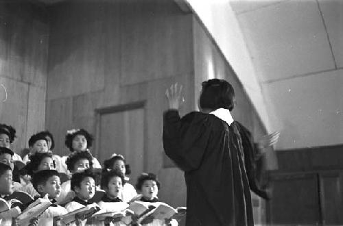 Coductor leading choir as they sing