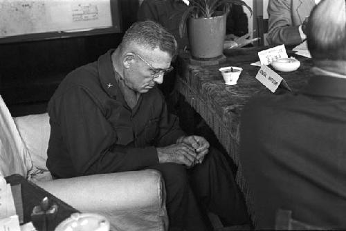 General observing his hands under table