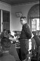 Soldier standing at middle of table holding out document