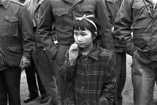 Little girl standing in front soldiers