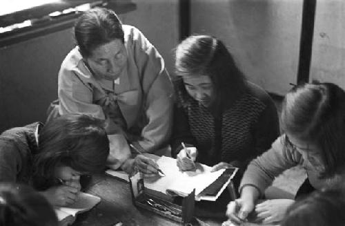 Woman at table helping children with assignment 2