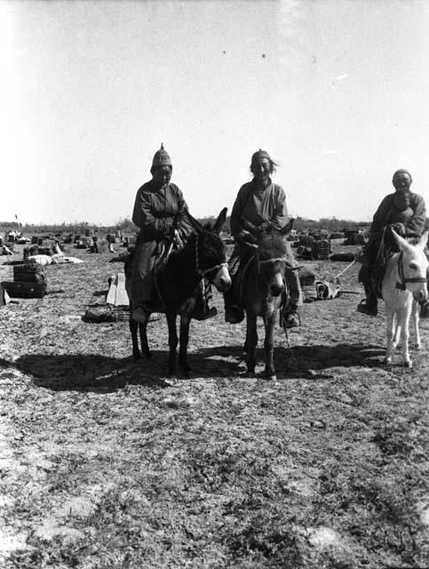 West Edsingol, 3 Torgut men on donkeys, camp supplies in background