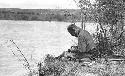 Owen Lattimore (?) sitting on a riverbank writing