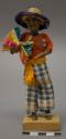 Doll, man with plant fiber bundle and straw hat, affixed to stand
