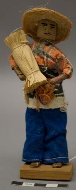 Doll, man with plant fiber bundle and straw hat, affixed to stand