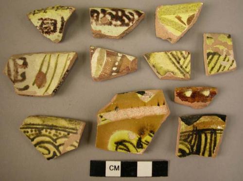 11 rim potsherds - glazed, painted with white, yellow and dark brown (local)