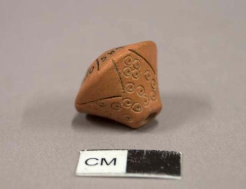 Ceramic bead, round with two tapered ends - one is longer, incised designs