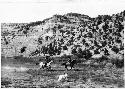 Men on horses by side of mountain