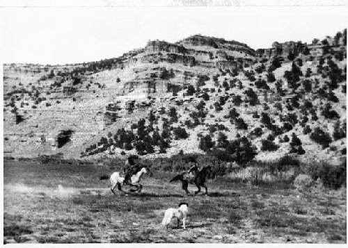 Men on horses by side of mountain