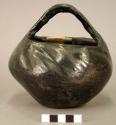 Pottery bowl with handle. Flat base, incurved rim, crude indented lines run dia