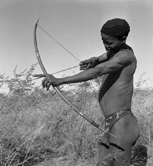 "/Qui Hunter" holding a bow and arrow, showing method of holding and releasing