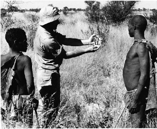 Robert Story holding a Polaroid picture for Oukwane and !Gai to see