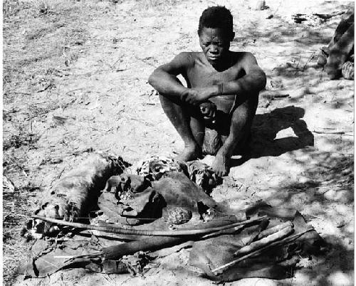 Oukwane sitting, with his possessions laid out on the ground in front of him