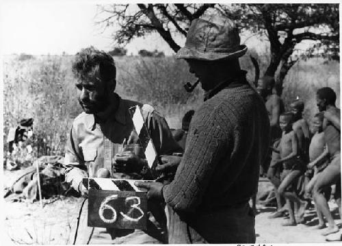 Group of people standing in the background, and Daniel Blitz and Casper Kruger in the foreground, showing how they put the numbers on the roll of film