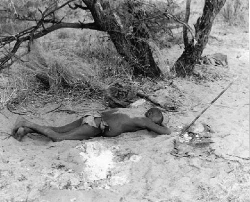 Oukwane lying on his stomach, with sand sprinkled on his back