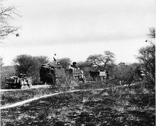 Expedition trucks waiting in burned-over land