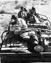 Group of people sitting on top of the expedition truck, including !Ungka, "/Qui Navel" and Lorna Marshall