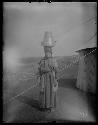 Woman standing next to tent with pot on her head